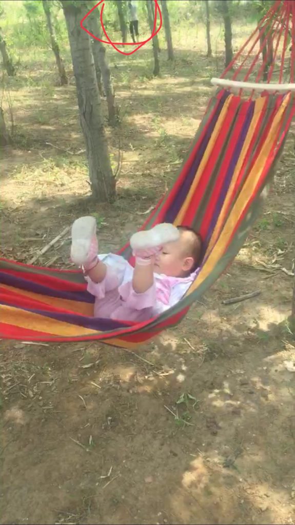 回老家 在老家的小山上挂了个吊床哄孩子 拍个朋友圈 后来发现镜头里多出来个人 可是附近当时根本没有人啊 吓人